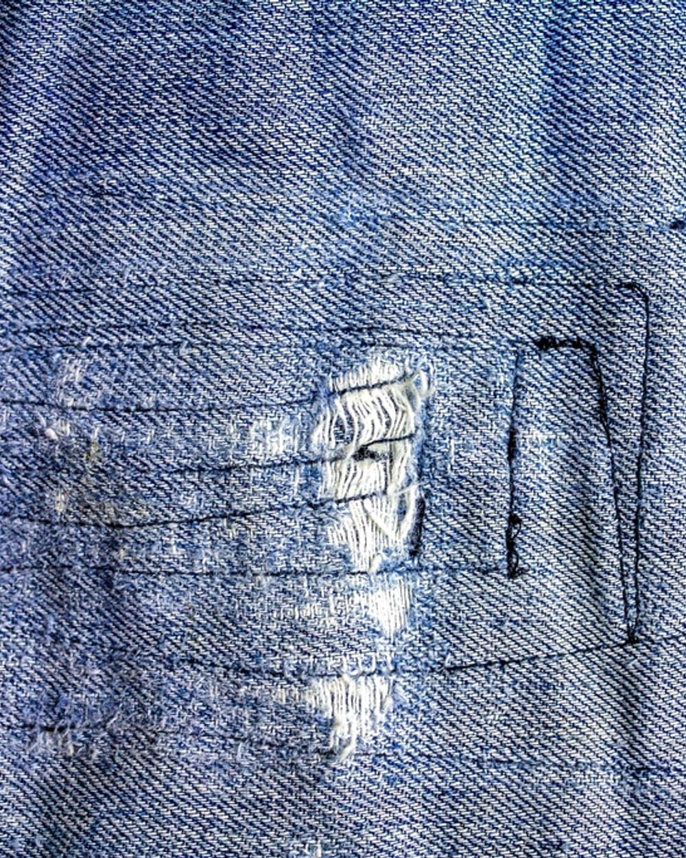 Llavero de denim con un zurcido hecho a mano sobre la tela gastada